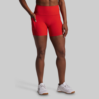 Person wearing red athletic shorts and white sneakers on a gray background