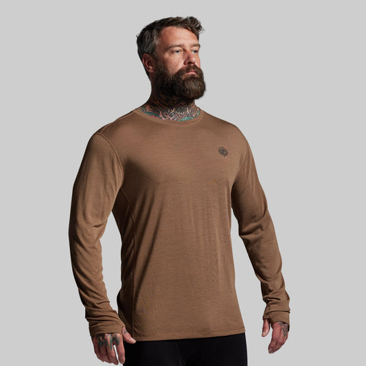 Man wearing a brown long-sleeve shirt against a gray background