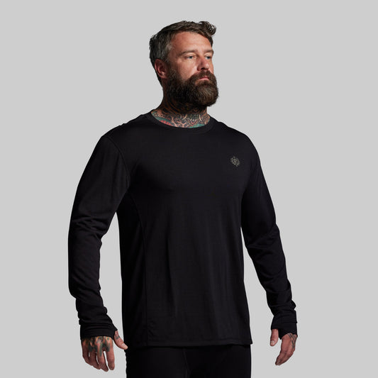 Man wearing a black long-sleeve shirt with a small logo on a gray background