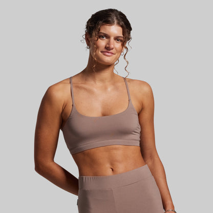 Woman wearing a brown sports bra and leggings against a gray background