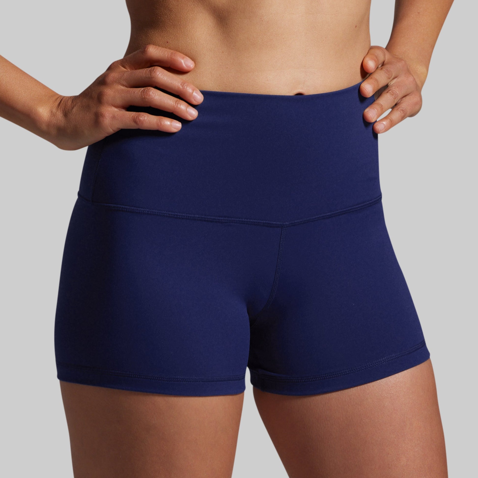 Person wearing navy blue athletic shorts on a plain background