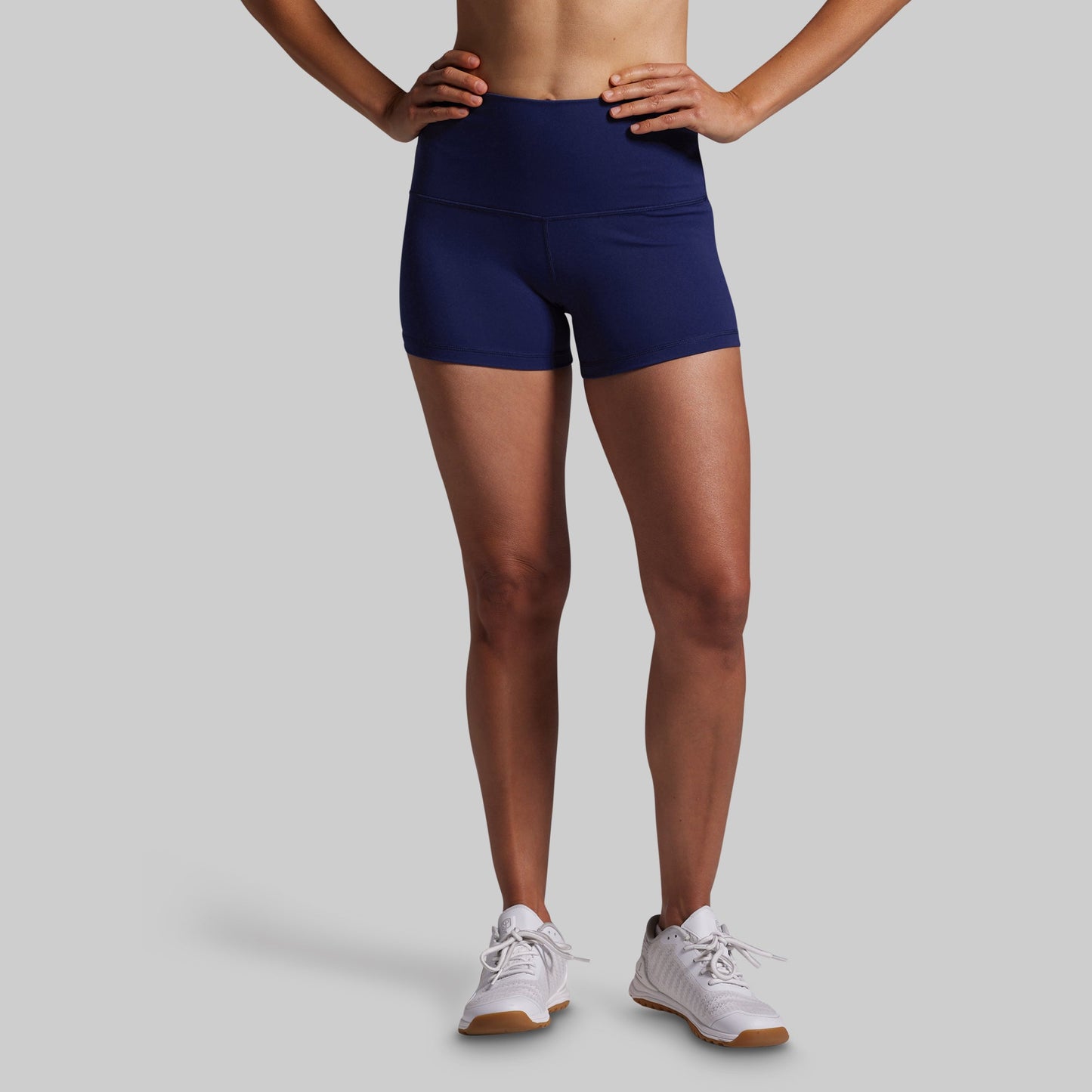 Person wearing navy blue athletic shorts on a gray background