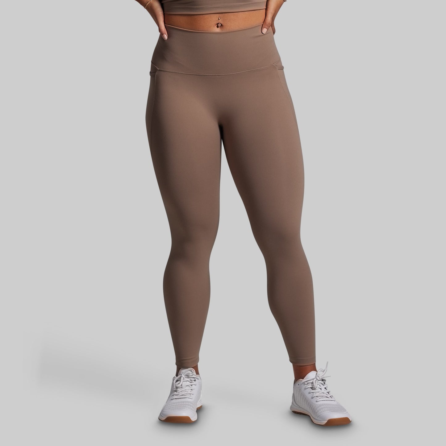 Person wearing brown leggings on a gray background