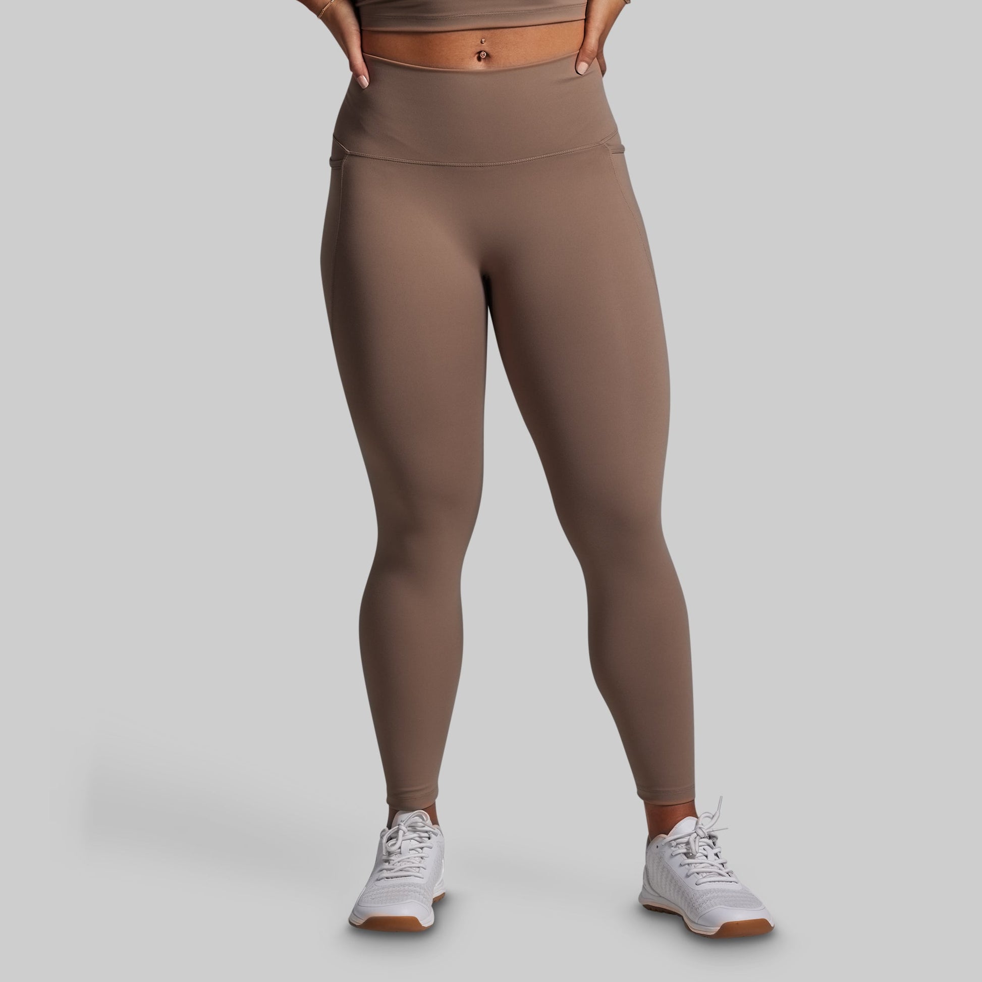 Person wearing brown leggings on a gray background