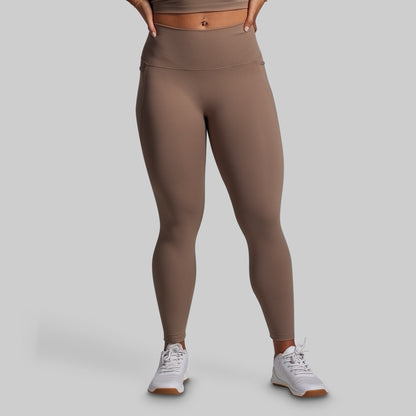 Person wearing brown leggings on a gray background