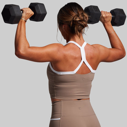 Woman lifting weights with a neutral background