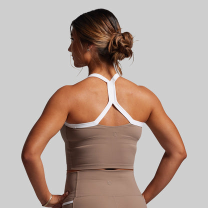 Woman wearing a brown and white sports outfit against a gray background