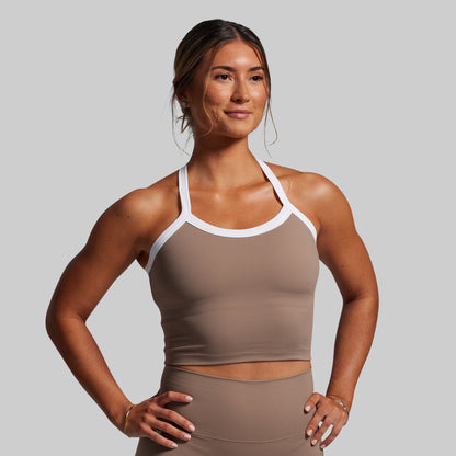 Woman wearing a beige sports bra and leggings on a plain background