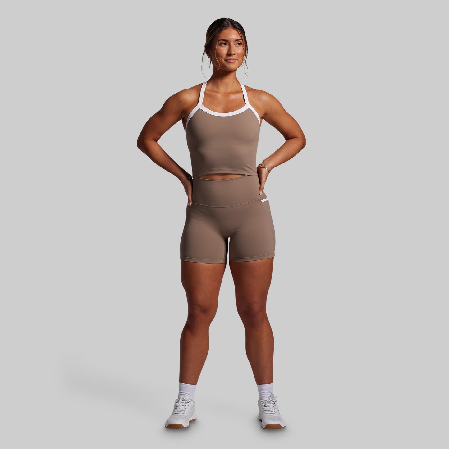 Woman wearing a brown athletic outfit on a gray background