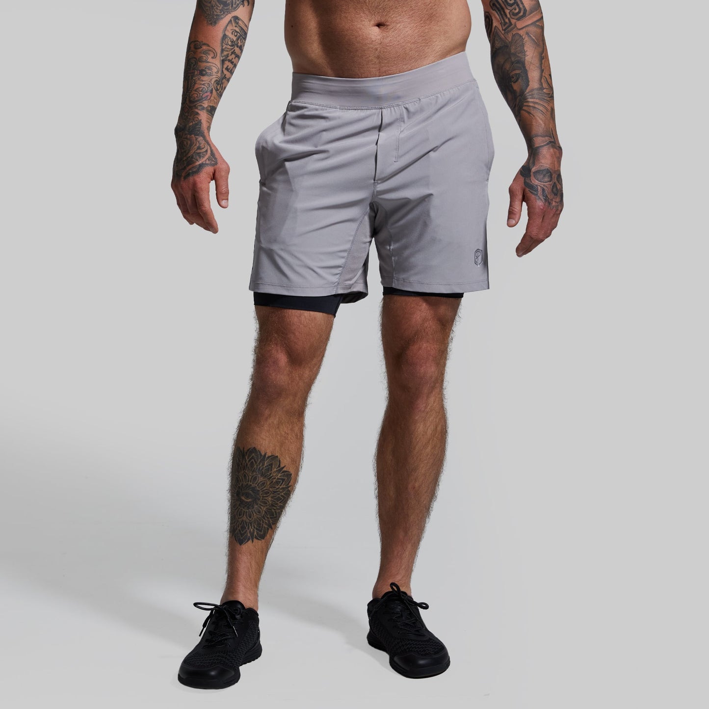 A pair of gray, versatile shorts with a compression inner lining, displayed on a person.