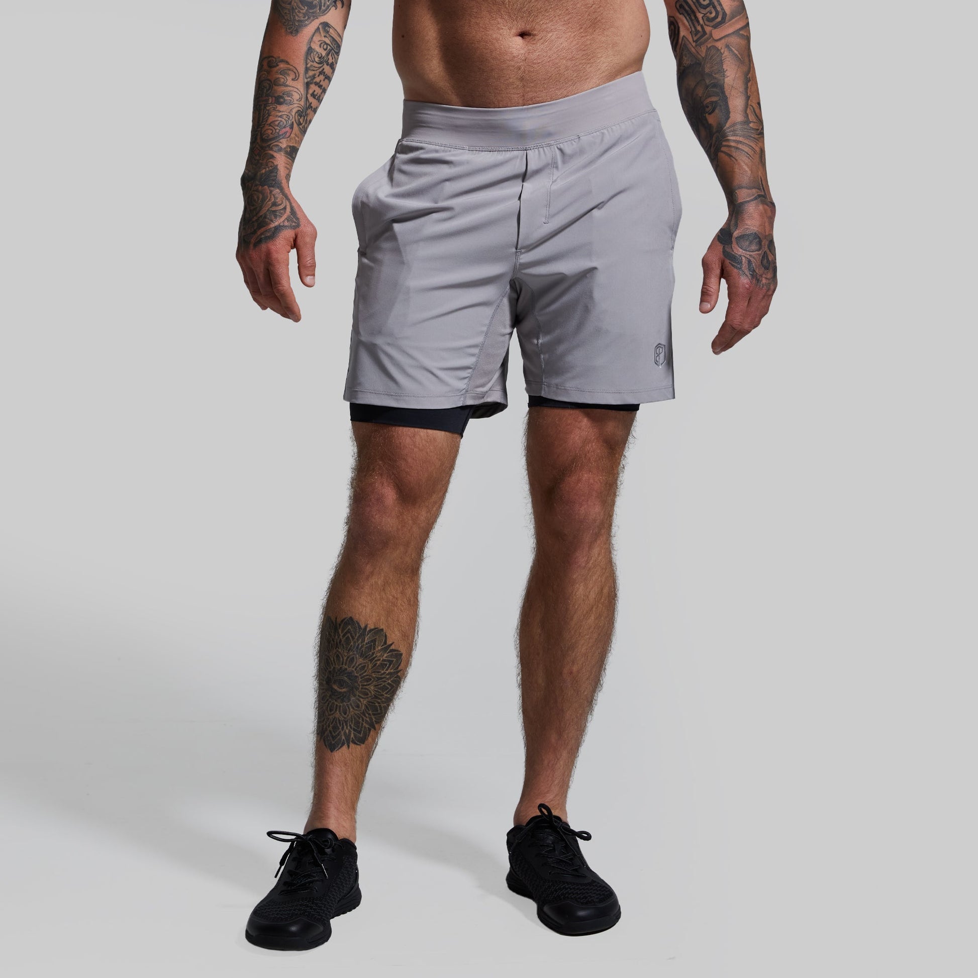 A pair of gray, versatile shorts with a compression inner lining, displayed on a person.