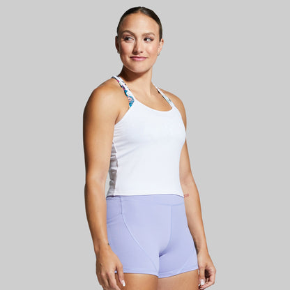 Woman wearing a white tank top and light purple shorts on a gray background