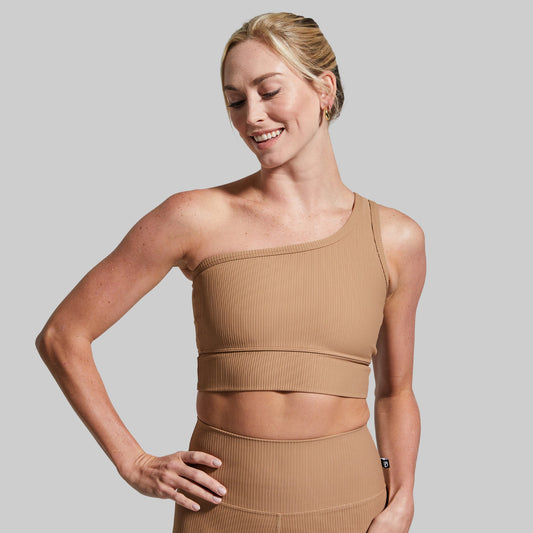 Woman wearing a beige athletic outfit on a plain background