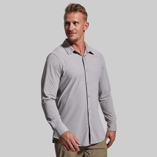 Man wearing a light gray button-up shirt with a plain background
