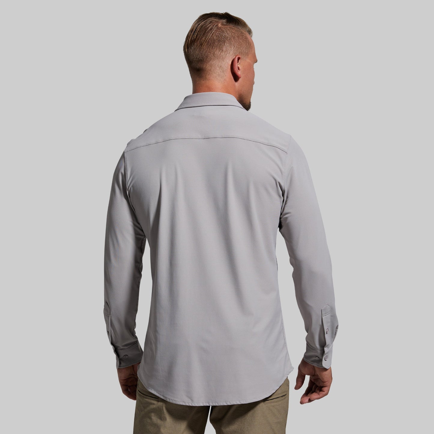 Man wearing a light gray long sleeve shirt with a plain background
