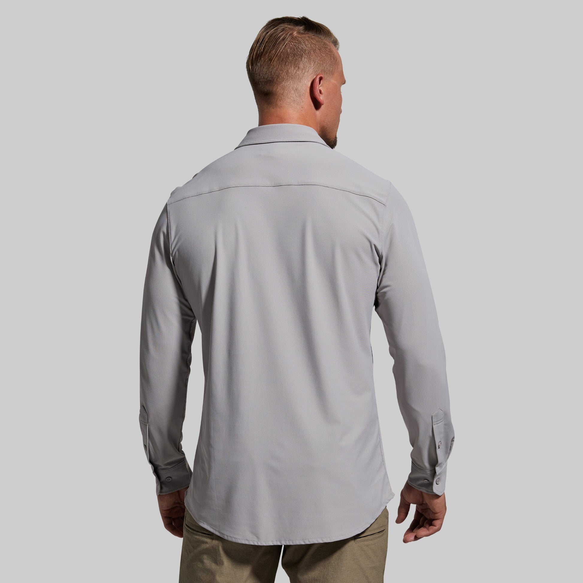 Man wearing a light gray long sleeve shirt with a plain background