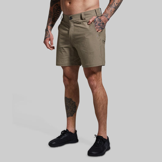 A male model wearing khaki-colored Traverse shorts and black shoes, standing against a white background.