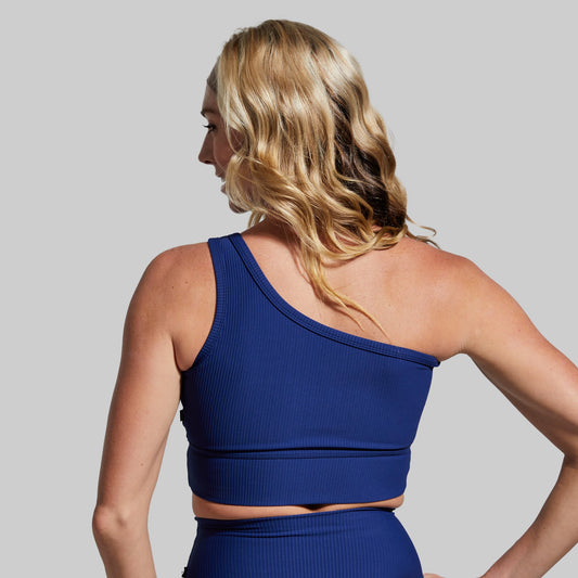 Woman wearing a blue sports bra and leggings against a gray background