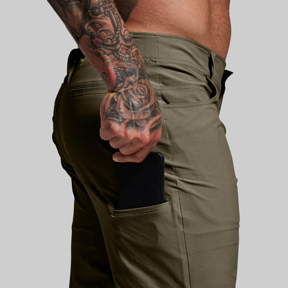 Close-up of man pulling a cell phone out of a side pocket on green pants.