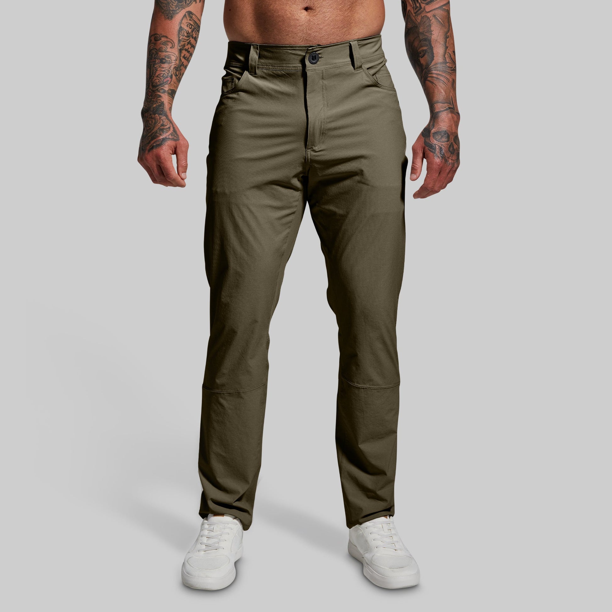 A male model wearing a pair of green Traverse Pants with a button-and-fly closure, belt loops, and standing upright.