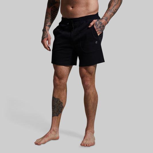 A male model wearing black lounge shorts with a textured surface, standing against a plain background.