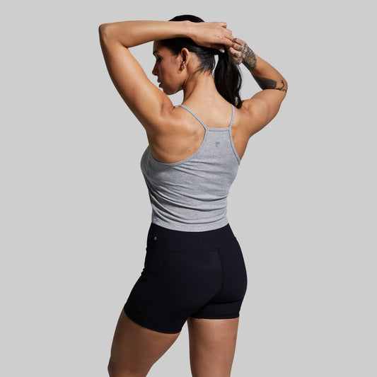 Woman wearing a gray tank top and black shorts against a plain background